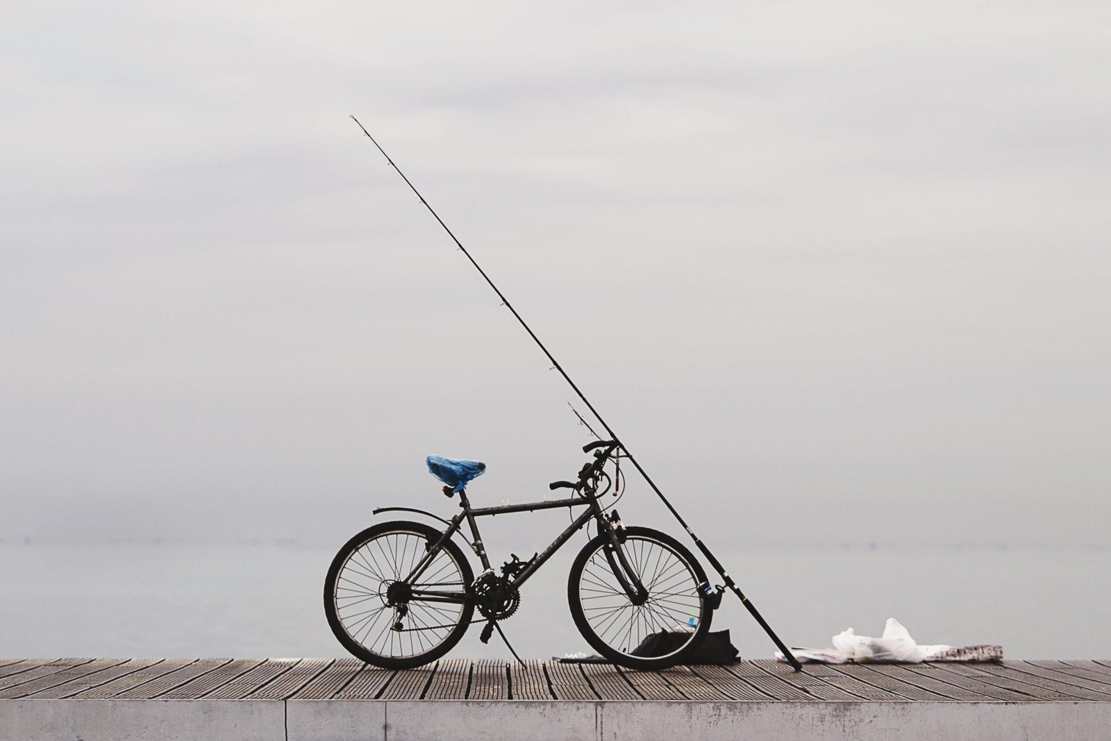 A vintage bicycle with fishing gear on a wooden pier overlooking the sea in Thessaloniki, Greece.