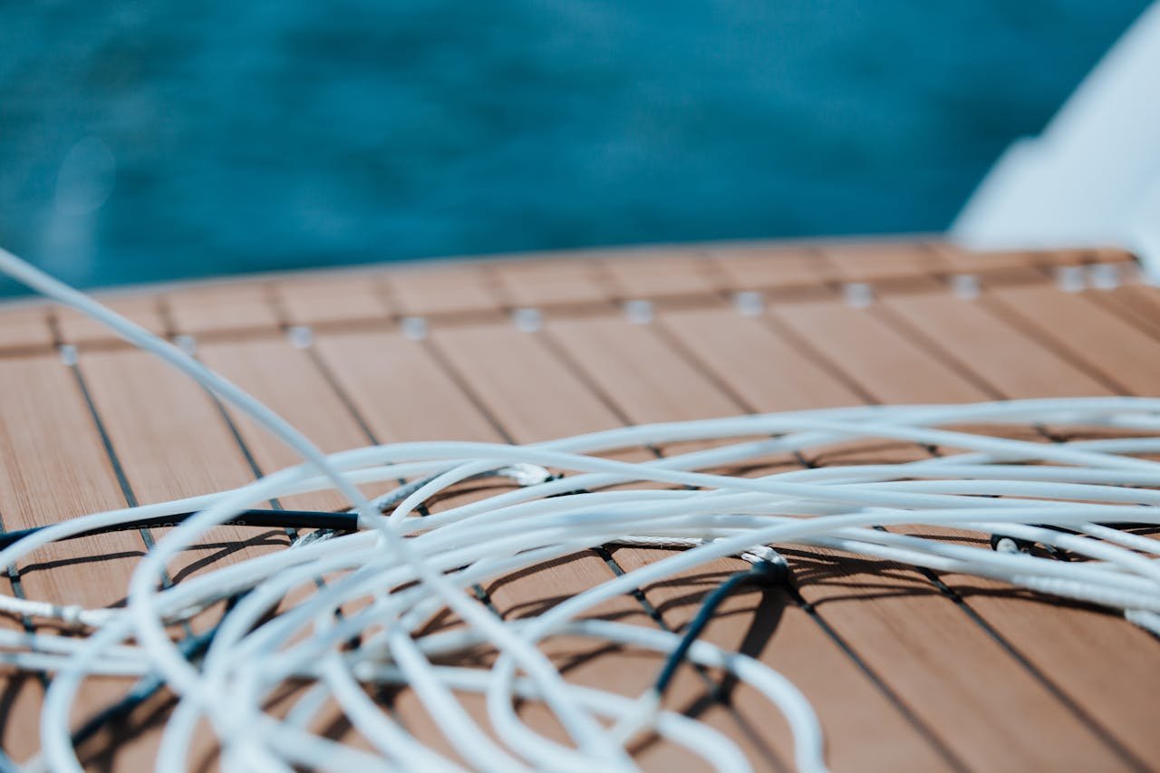 Close-up of coiled rope on a wooden deck with ocean background. Ideal for nautical themes.